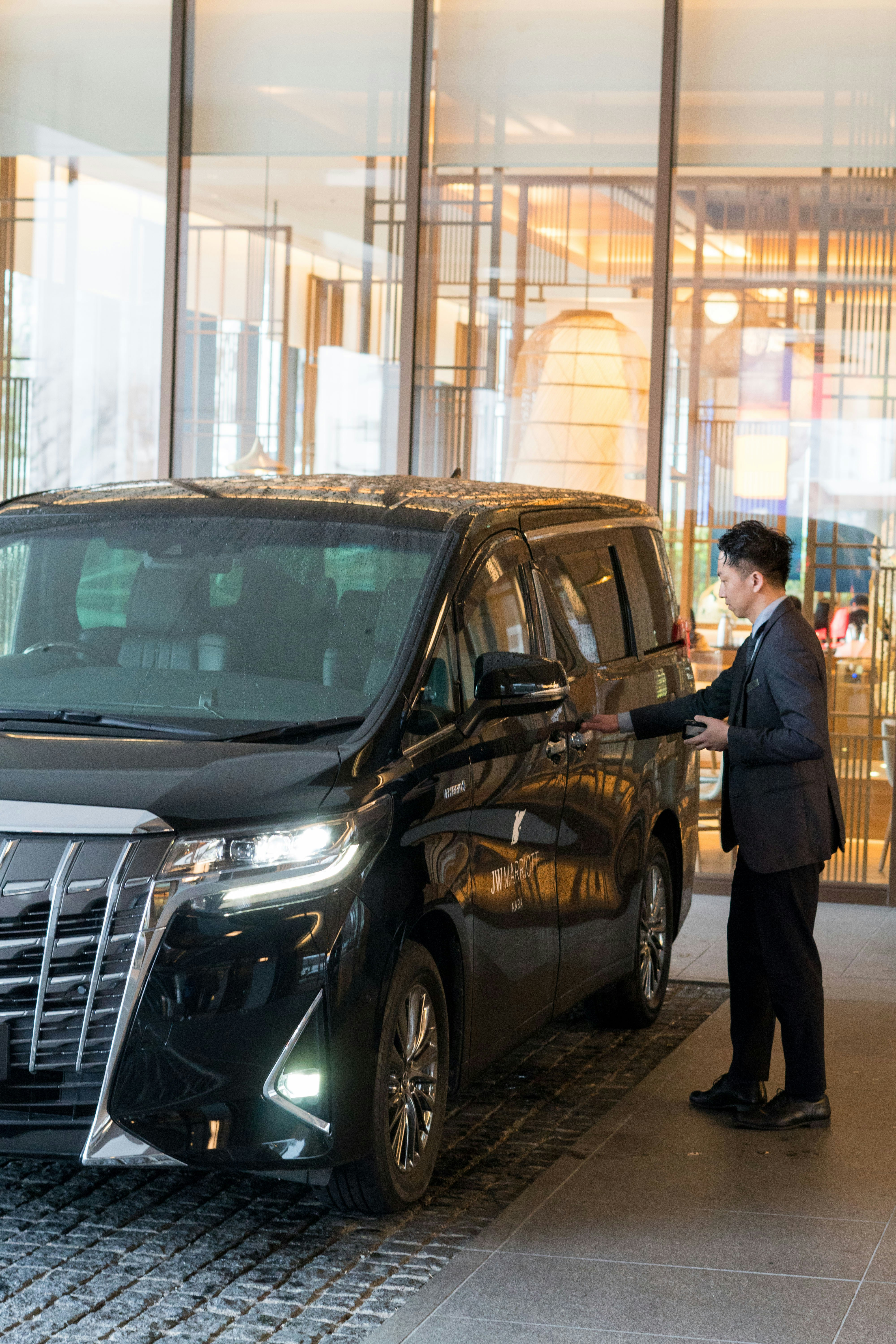 Chauffeur opening car door at luxury hotel